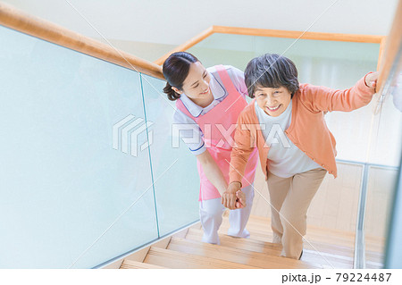 階段を登るシニア女性と介護スタッフ 79224487