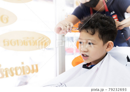 Cute asian child boy getting hair cut by hairdresser at hair salon. Hair care and childhood lifestyle concept. 79232693
