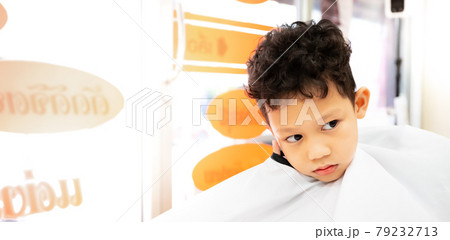 Cute asian child boy getting hair cut by hairdresser at hair salon. Hair care and childhood lifestyle concept. 79232713