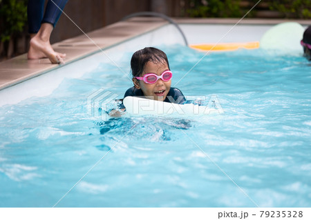 Asian child girl playing water and swimming in the swimming pool with her friend with fun. Summer activity and childhood lifestyle concept. Asian child girl playing water and swimming in the swimming pool with her friend with fun. Summer activity and childhood lifestyle concept. 79235328