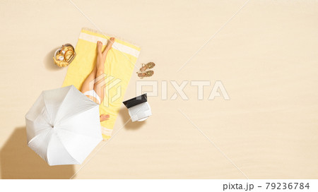 Woman in bikini with laptop, bag, headphones sitting on the beach towel near sea coastline under umbrella. Summer vacation. Aerial view.16:9 Woman in bikini with laptop, bag, headphones sitting on the beach towel near sea coastline under umbrella. Summer vacation. Aerial view.16:9 79236784