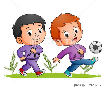 The two boys are playing the football and kicking the ball in the field The two boys are playing the football and kicking the ball in the field 79237378