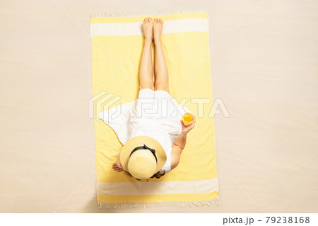 Alone woman in straw hat and dress sitting on yellow beach towel and drinking orange juice. summer. Top, aerial view 79238168