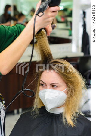 Drying hair with a hair dryer and a round brush, hairdressing procedures. Drying hair with a hair dryer and a round brush, hairdressing procedures. 79238355