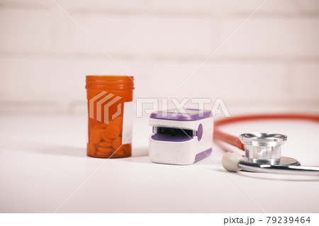 pill container, stethoscope and pulse oximeter on table  79239464