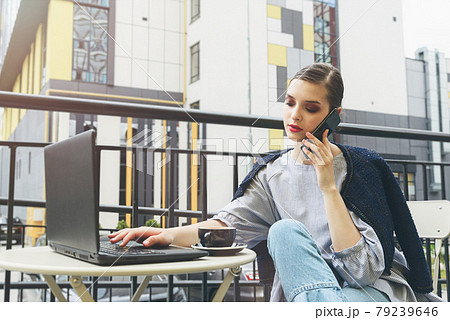 Charming happy woman student communicates by phone and use laptop computer to prepare for the course work. 79239646
