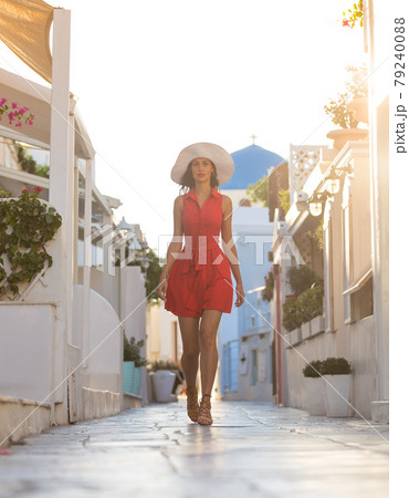 Santorini travel tourist brunette woman in red dress visiting famous white Oia village. Santorini travel tourist brunette woman in red dress visiting famous white Oia village. 79240088