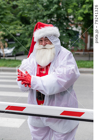Santa Claus in a protective suit outdoors during the coronavirus epidemic 79241326