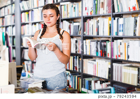 Teenage girl customer is choosing new book Teenage girl customer is choosing new book 79243594