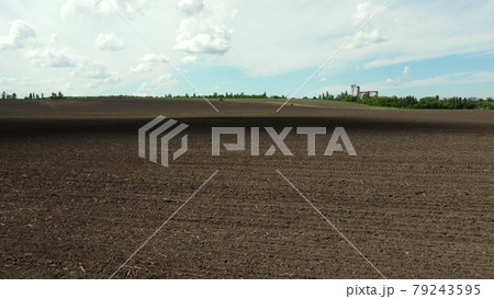 Aerial drone view flight over huge plowed field and blue sky. Aerial drone view flight over huge plowed field and blue sky. 79243595