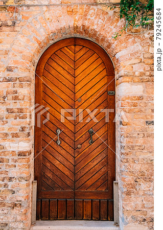 An old beautiful brown wooden door in a brick building. 79245684