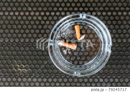 Cigarette butt in an ashtray on black metal background Cigarette butt in an ashtray on black metal background 79245717