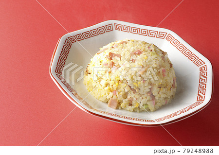 鳴門巻きやチャーシューなど色々な具材が入った熱々の五目チャーハンを赤色の背景で撮影 79248988