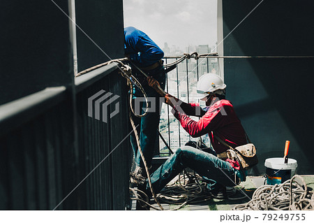 Two painter worker hands pulling the rope working on top of building. Two painter worker hands pulling the rope working on top of building. 79249755