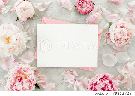 Mockup invitation, blank paper greeting card, pink envelope and peonies on gray stone table. Flower background. Flat lay, top view. Mockup invitation, blank paper greeting card, pink envelope and peonies on gray stone table. Flower background. Flat lay, top view. 79252725