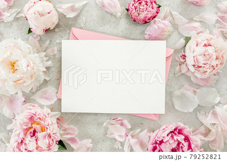 Mockup invitation, blank paper greeting card, pink envelope and peonies on gray stone table. Flower background. Flat lay, top view. Mockup invitation, blank paper greeting card, pink envelope and peonies on gray stone table. Flower background. Flat lay, top view. 79252821