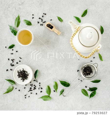 Herbal tea with two white tea cups and teapot, with green tea leaves. Flat lay, top view. Tea concept 79253027