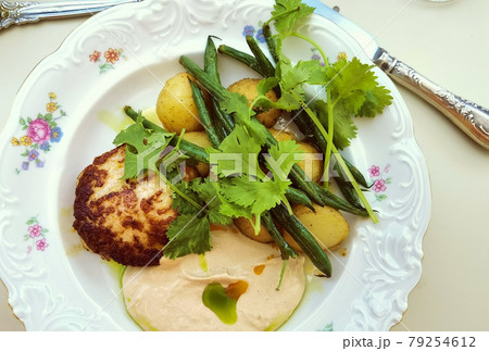 chicken cutlet with herbs and hummus on a white plate 79254612