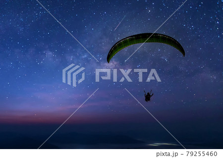 Skydiving night landscape of parachutist flying in soft focus. 79255460