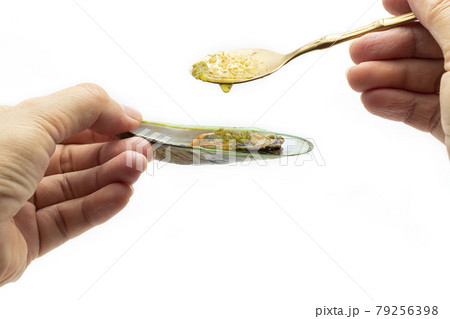 One handheld mussels in the lid, the other was pouring the spicy sauce over the mussels against a white background. One handheld mussels in the lid, the other was pouring the spicy sauce over the mussels against a white background. 79256398