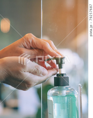 Hands of senior woman pressed blue alcohol gel bottle to prevent the spreading of the Coronavirus (Covid-19) before entrance to cafeteria. Healthcare concept. New normal lifestyle. Selective focus 79257687