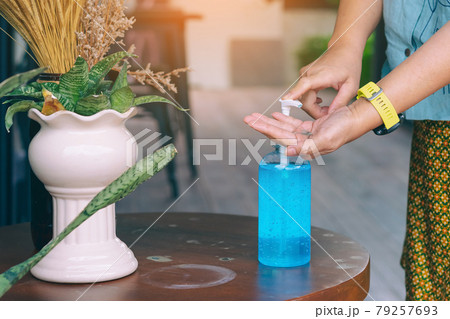 Hands of senior woman pressed blue alcohol gel bottle to prevent the spreading of the Coronavirus (Covid-19) before entrance to cafeteria. Healthcare concept. New normal lifestyle. Selective focus Hands of senior woman pressed blue alcohol gel bottle to prevent the spreading of the Coronavirus (Covid-19) before entrance to cafeteria. Healthcare concept. New normal lifestyle. Selective focus 79257693