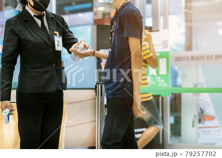 Hand of customer waits for a drop of alcohol gel from female security guard to prevent the spread of germs and bacteria and avoid infections Corona virus (Covid-19) before entering the mall. 79257702