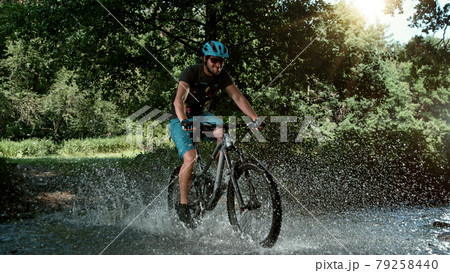 Mountain biker speeding through forest stream. 79258440