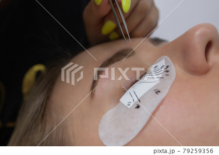 Beautiful Woman with long eyelashes in a beauty salon. Eyelash extension procedure. Lashes close up. 79259356
