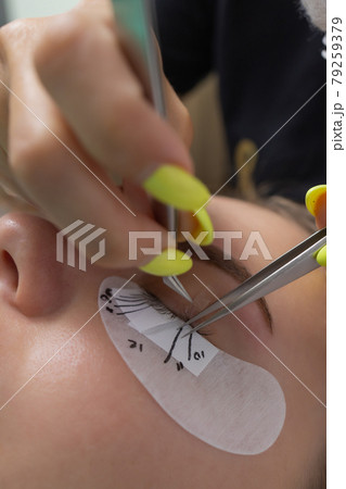 Beautiful Woman with long eyelashes in a beauty salon. Eyelash extension procedure. Lashes close up. 79259379