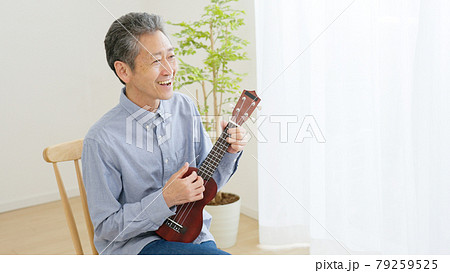 家でウクレレを弾くシニア男性 79259525