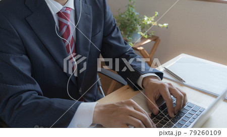 自宅で仕事をするビジネスマン。イヤホンをつけてノートパソコンを操作する男性。 79260109