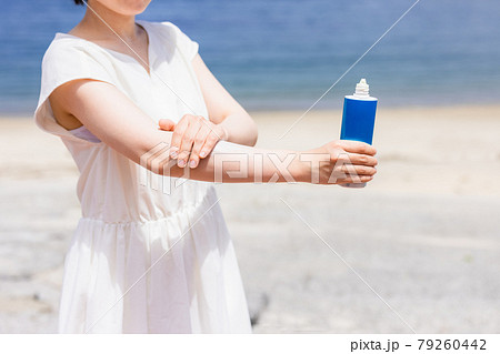 海で日焼け止めクリームを塗る若い女性 79260442