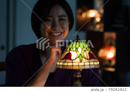 ステンドグラスランプを点ける女性 79262912