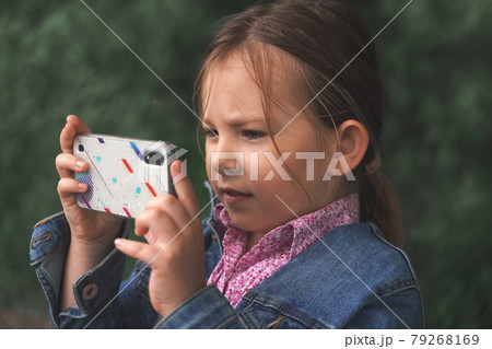Little Caucasian girl taking pictures on her smartphone photo camera 79268169