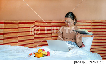 Picture of tourists used laptop and eating fruits on the bed in the luxury hotel room, healthy food concept 79269648