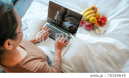 Picture of tourists hand used laptop and eating fruits on the bed in the luxury hotel room, healthy food concept 79269649