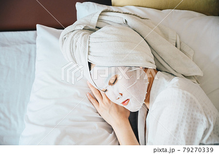 Portrait of young woman sleeping on bed while applying facial mask on her face. Conceptual of young woman lifestyle in her private room. 79270339