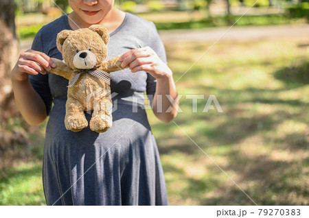 Cropped image of lovely mother holding cute bear doll. Conceptual shot of healthy pregnant woman feeling and expectation for her baby. Cropped image of lovely mother holding cute bear doll. Conceptual shot of healthy pregnant woman feeling and expectation for her baby. 79270383