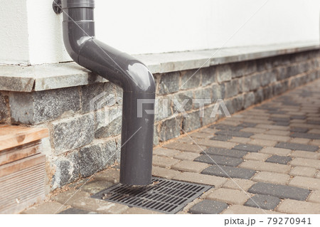 stormwater pipe on facade with rainwater drainage into drainage system with sewer manhole grill 79270941