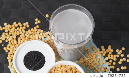 Soy milk blended with black sesame in clear glass on black plate mat. Black sesame seed and soy beans in a cup. Black sesame soy bean blended milk. Healthy drink with natural ingrediant. Soya milk. 79274725