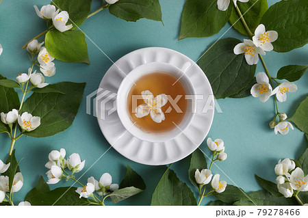 cup of tea with jasmine flowers on green background. Flat lay, top view 79278466
