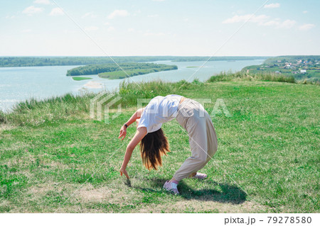 slim beautiful woman doing yoga and stretching outdoors. young woman exercising alone on a river bank. person enjoying summer active lifestyle 79278580
