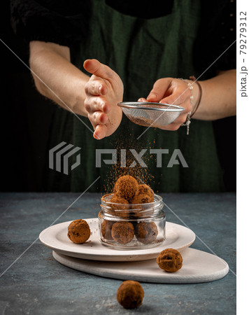 A woman sprinkle the chocolate balls with cocoa powder. Healthy kitchen concept A woman sprinkle the chocolate balls with cocoa powder. Healthy kitchen concept 79279312