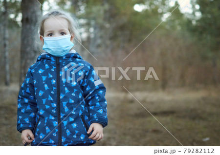Little girl with protective mask looking in front in park outdoor walk in forest Little girl with protective mask looking in front in park outdoor walk in forest 79282112