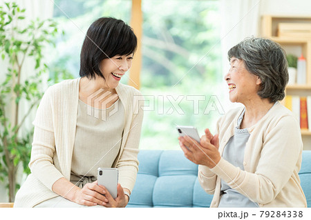 スマホを見ながら仲良く会話をする親子　　嫁姑　母子　シニア女性　ミドル女性　2人 79284338