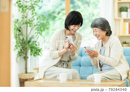 スマホを見ながら仲良く会話をする親子　　嫁姑　母子　シニア女性　ミドル女性　2人 79284340