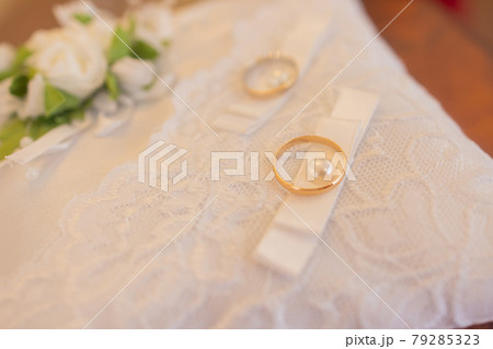 Close-up view of golden wedding rings on decorative white lace pillow. Close-up view of golden wedding rings on decorative white lace pillow. 79285323