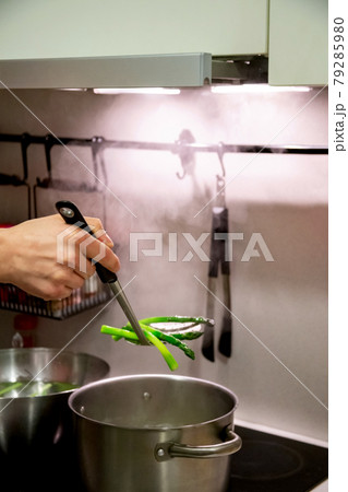 The cook took out hot, boiled asparagus from a large pot. The cook took out hot, boiled asparagus from a large pot. 79285980
