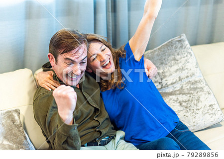 Mature couple celebrating something they are watching on TV. Mature couple celebrating something they are watching on TV. 79289856